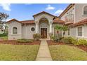 Inviting home entrance featuring a tile roof, landscaped yard, and double doors framed by elegant columns at 10616 Emerald Chase Dr, Orlando, FL 32836