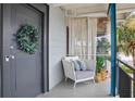Cozy porch with stylish chair, decorative pillows, and a welcoming wreath on the gray front door at 151 N Orlando Ave # 229, Winter Park, FL 32789