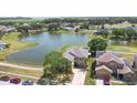 Waterfront home featuring mature landscaping, a paved driveway, and solar panels at 2260 The Oaks Blvd, Kissimmee, FL 34746