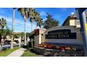 Welcoming entrance to Townhomes at Flora Ridge, featuring lush landscaping and a decorative stone wall at 2952 Ashland S Ln, Kissimmee, FL 34741