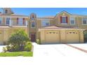 Inviting townhome featuring a two-car garage, light-colored exterior, and contrasting red shutters at 2952 Ashland S Ln, Kissimmee, FL 34741