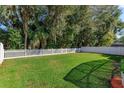 Lush green backyard with a classic white picket fence, offering privacy and charm at 4963 Rock Rose Loop, Sanford, FL 32771