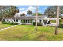 Spacious home featuring lush green lawn, mature trees, and a covered carport on the side at 803 N Shore Dr, Leesburg, FL 34748