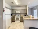 A well-lit kitchen features tiled floors, grey cabinets, and white appliances at 3175 Feltrim Pl # 304, Kissimmee, FL 34747