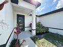 A covered entryway with a modern front door and well-maintained landscaping at 345 Gardenia Ct, Kissimmee, FL 34759