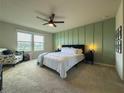 Stylish bedroom with an upholstered bed frame, a green accent wall, and ample natural light at 5017 Blue Hammock Ct, Kissimmee, FL 34746