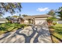 A single-story home with a two car garage and a long paved driveway with a green yard at 7609 Sandstone Dr, Orlando, FL 32836