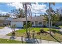 Well-kept house featuring a two-car garage, mature trees, and a green front yard at 2665 Windsor Heights St, Deltona, FL 32738