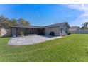 Wide view of backyard with paved patio, enclosed porch, and well maintained lawn at 825 Rosemere Cir, Orlando, FL 32835
