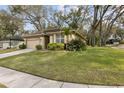 Tan single-story home with mature trees, green lawn, and attached garage at 892 Cool Springs Cir, Ocoee, FL 34761