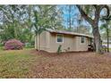 Side view of a tan home showing yard covered in leaves and surrounding landscape at 14226 Nell Dr, Orlando, FL 32832