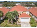 Aerial view of a two-story home with a red tile roof, palm trees, a well-manicured lawn, and a two-car garage at 1520 Solana Cir, Davenport, FL 33897