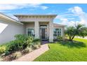 Inviting front entrance with brick walkway, lush landscaping, and a modern-style covered entryway at 4068 Stone Creek Loop, Lake Wales, FL 33859