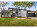 Contemporary two-story house boasts mature trees, fresh landscaping, and an attached two-car garage at 4940 Spring Run Ave, Orlando, FL 32819