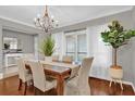 Elegant dining room with a wooden table, chandelier, and large windows with white curtains at 7545 Lake Dr, Belle Isle, FL 32809