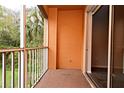 A balcony with orange walls looking out onto lush green foliage at 8775 Sartori St # 208, Orlando, FL 32829