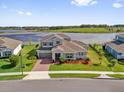 Aerial view of a two-story home with a manicured lawn, brick driveway, and stunning lake views at 16828 Sanctuary Dr, Winter Garden, FL 34787
