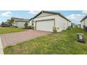 Beautiful home with a brick-paved driveway, two-car garage, and lush green lawn at 3069 Cassidy Ln, Haines City, FL 33844