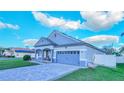 View of home featuring a two-car garage, covered porch, and a beautiful driveway and manicured lawn at 523 Cascading Creek Ln, Winter Garden, FL 34787