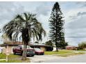 Exterior view of a single-story home with a large tree and well-maintained landscaping. Red truck and car in driveway at 5371 Tribune Dr, Orlando, FL 32812