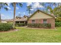 Inviting home featuring a brick accent wall, lush landscaping, and a well-maintained lawn at 743 Riverbend Blvd, Longwood, FL 32779