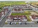 Extensive aerial view of a townhome community with ample parking, green spaces, and surrounding trees at 7558 Sunflower Cir, Kissimmee, FL 34747