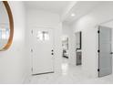 Bright foyer featuring white walls, decorative mirror, and sleek tile flooring at 7633 Marietta St, Orlando, FL 32807