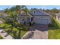 Inviting single-Gathering home with a manicured lawn, brick-paved driveway, and an attached two-car garage at 10012 Lovegrass Ln, Orlando, FL 32832