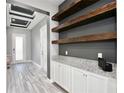 Hallway with floating shelves, gray walls, white cabinets, and wood-look tile floor at 14103 Alafaya Oak Bnd, Orlando, FL 32828