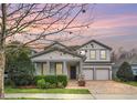 Charming two-story home with a manicured lawn, brick driveway, and a welcoming front porch with stone accents at 14150 Aldford Dr, Winter Garden, FL 34787