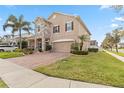 Two-story home showcasing a blend of stone and stucco, complemented by a brick driveway and manicured lawn at 1700 Leatherback Ln, St Cloud, FL 34771