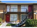 Exterior shot showcasing apartments with stairs leading up to the second level, featuring red doors and black railings at 1909 Caralee Blvd # 4, Orlando, FL 32822