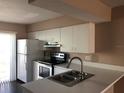 A view of the kitchen features white cabinets, stainless steel appliances, and a double sink with a faucet at 1909 Caralee Blvd # 4, Orlando, FL 32822