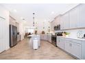 Spacious kitchen with gray cabinets, stainless steel appliances, a center island, and sleek tile flooring at 1920 Perch Hammock Loop, Groveland, FL 34736