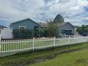 Single-story home with blue exterior, well-manicured shrubs and bushes, and a white picket fence at 214 Great Yarmouth Ct, Kissimmee, FL 34758