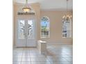 Bright foyer with decorative glass doors, chandelier, and neutral tile flooring creates a grand entrance at 2732 Aloma Oaks Dr, Oviedo, FL 32765