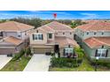 Aerial view of a two-story home with a tile roof, landscaped yard and proximity to neighboring houses at 7587 Oakmoss Loop, Davenport, FL 33837