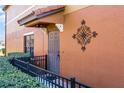 Inviting front porch featuring an ornate metal decoration, privacy bushes and a gray entry door at 9568 Muse Pl, Orlando, FL 32829