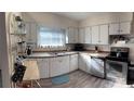 Well-lit kitchen featuring ample white cabinetry, stainless steel appliances, and modern flooring at 1404 High St, Leesburg, FL 34748