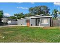 View of well-maintained home featuring a gray exterior, unique roofline, and landscaped front yard at 1627 Triangle Ave, Orlando, FL 32806