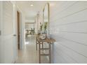 Bright hallway featuring white shiplap walls, tile flooring, and a decorative console table with a mirror at 3001 Moulin Rd, Davenport, FL 33837