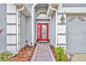 Close-up of a vibrant red front door with decorative plants and a well-maintained walkway at 3455 Bellingham Dr, Orlando, FL 32825