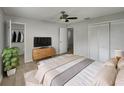 Bedroom features a ceiling fan, TV atop dresser, closet, and plant near an open bathroom at 437 Georgia Ave, St Cloud, FL 34769