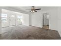 Bright living room with neutral carpet, ceiling fan, and a view to the front door and tiled laundry room at 1622 Dolphin Dr, St Cloud, FL 34771