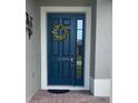 Stylish blue front door featuring a decorative wreath and side window, enhancing curb appeal at 2475 Verde View Dr, Apopka, FL 32703