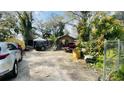 Wide view of a cluttered front yard with vehicles and overgrown foliage at 2516 Cannon St, Lakeland, FL 33815