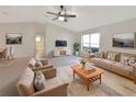 Bright living room with neutral tones, a ceiling fan, tile flooring, and ample natural light from a large window at 30 Hemlock Trce, Ocala, FL 34472