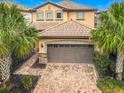 Front exterior view of a two-story house featuring a brick driveway and a two-car garage at 8941 Rhodes St, Kissimmee, FL 34747