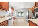 Bright kitchen with stainless steel appliances, granite countertops, wooden cabinetry, and a large window overlooking the backyard at 12853 Maryland Woods Ct, Orlando, FL 32824