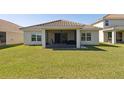 A covered back porch with dark furniture and a large lawn is perfect for entertaining at 1330 Bucktail Ct, Kissimmee, FL 34746